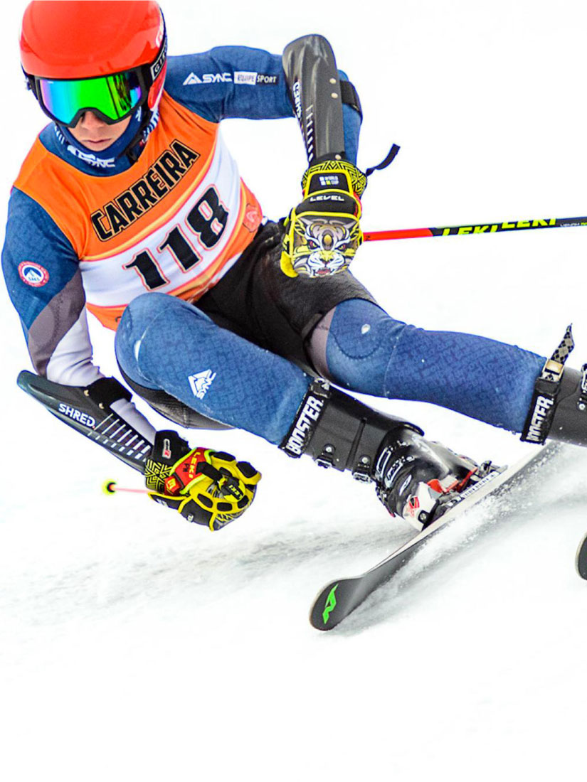 Skieur faisant une course et portant un dossard de compétition de ski alpin imprimé.