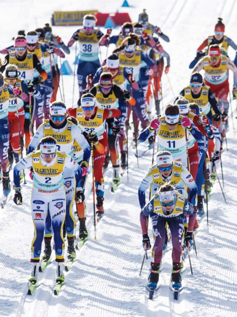 Départ d'une course de ski de fond avec des athlètes portant des dossards de course imprimés avec leur numéro.