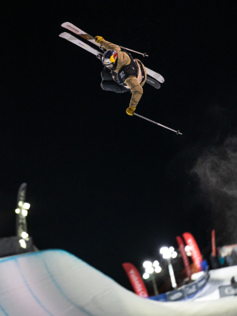 Athlète effectuant une acrobatie halfpipe en ski et portant un dossard imprimé Sécuri-Sport.